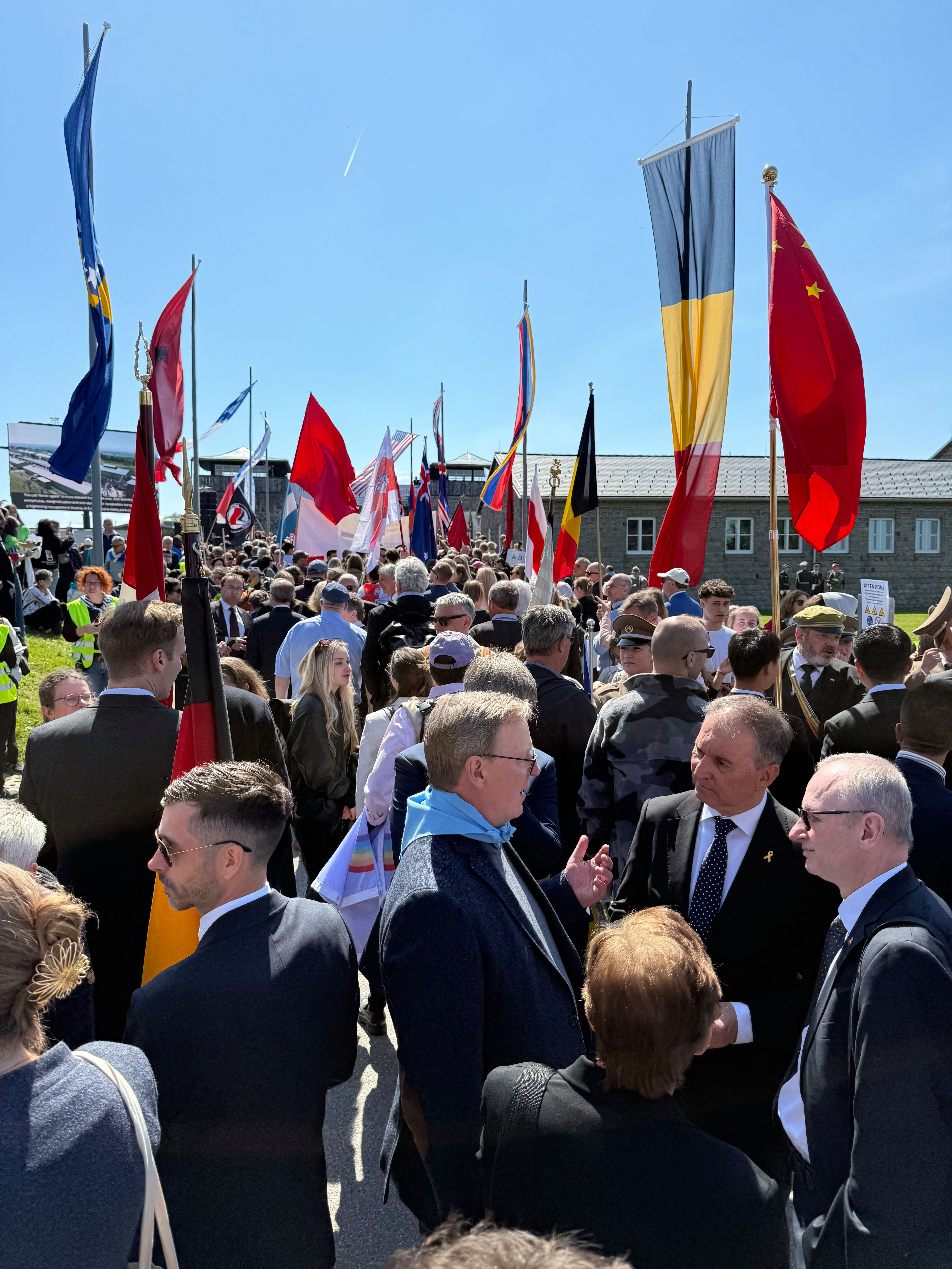 enschenmenge mit internationalen Fahnen bei einer Gedenkveranstaltung im ehemaligen Konzentrationslager Mauthausen.