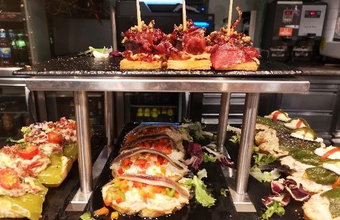Teller mit verschiedenen baskischen Pintxos – kleine belegte Brote mit Gemüse, Fisch und Fleisch – in einer Bar ausgestellt.